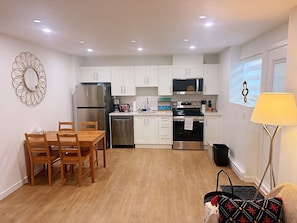 Una cocina moderna con armarios blancos, electrodomésticos de acero inoxidable y una zona de comedor con mobiliario de madera.