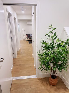 Ein Flur mit Holzboden, einem Blumentopf und einer weißen Wand.