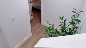 Kapea käytävä, jossa on portaikko, joka johtaa makuuhuoneeseen. Etualalla näkyy kasvi.