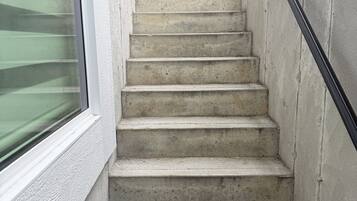 A concrete staircase with a metal handrail leading to a wooden door.