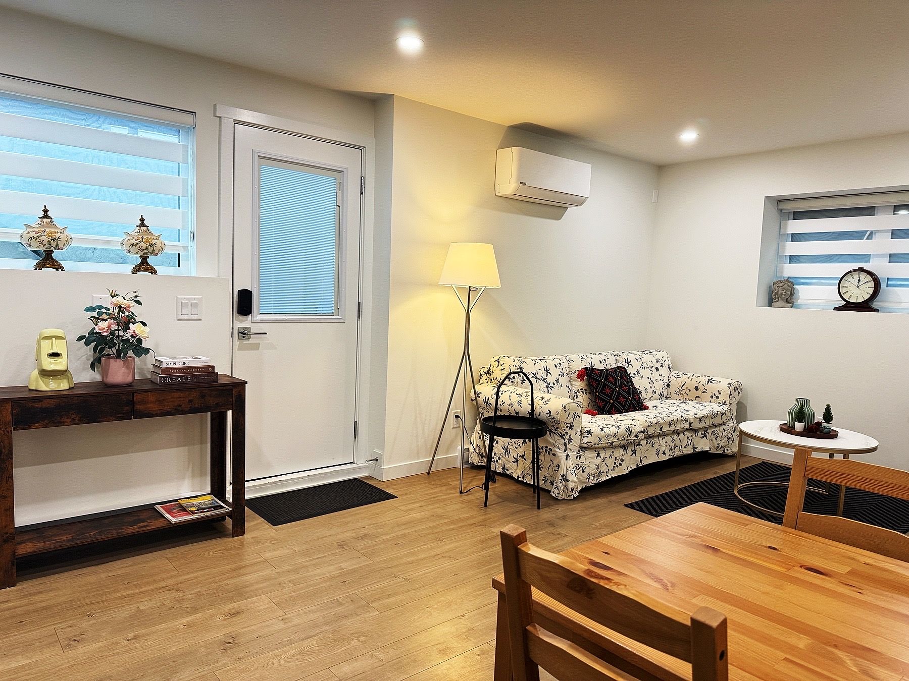 A cozy living room with a sofa, a coffee table, a lamp, and a small table with decorative items.