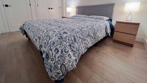 Makuuhuone, jossa on sänky, yöpöytälamput, yöpöytä ja vaatekaappi.