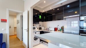 A modern kitchen with a built-in washing machine, a microwave, and a sink. - NEW - Comfortable and central apartment in Lisbon • Between Praça de Espanha and Sete Rios (Lisboa)
