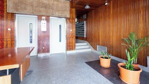 A reception area with a wooden reception desk, two doors, a staircase, and potted plants. - NEW - Comfortable and central apartment in Lisbon • Between Praça de Espanha and Sete Rios (Lisboa)