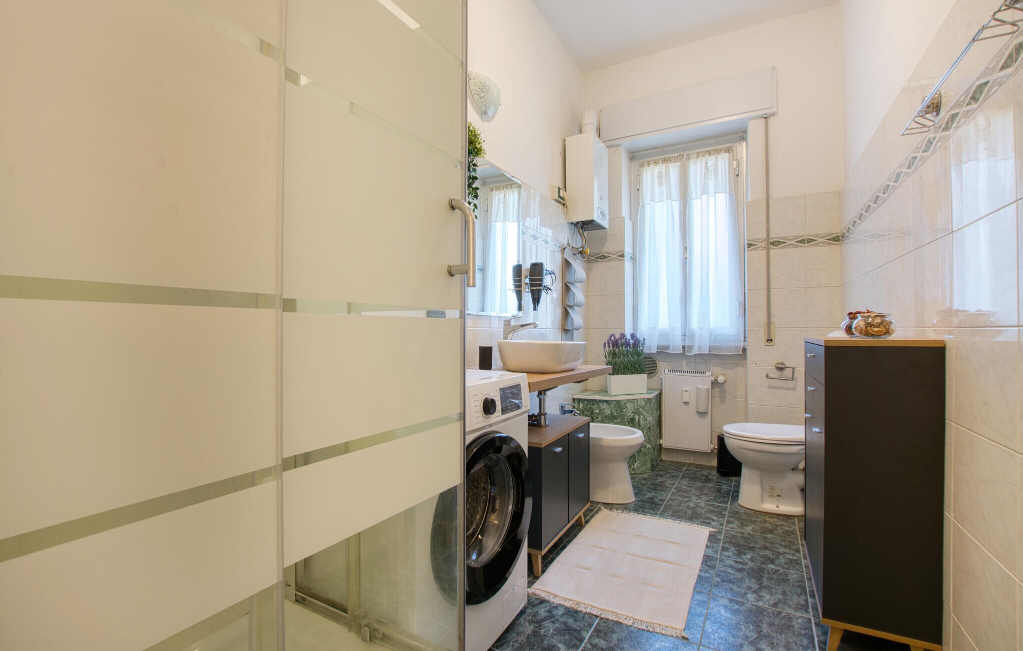 A compact bathroom with a washing machine, a sink, and a toilet.