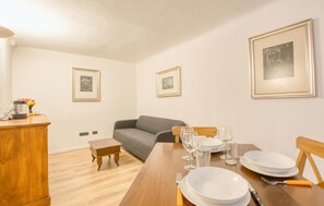 A dining area with a wooden table set for four, a grey sofa, and framed pictures on the walls. - Amazing apartment in Genova with WiFi (Genova)