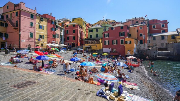 Una spiaggia affollata con ombrelloni colorati e persone che prendono il sole.
