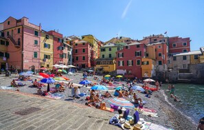 Ein überfüllter Strand mit bunten Sonnenschirmen und badenden Menschen.