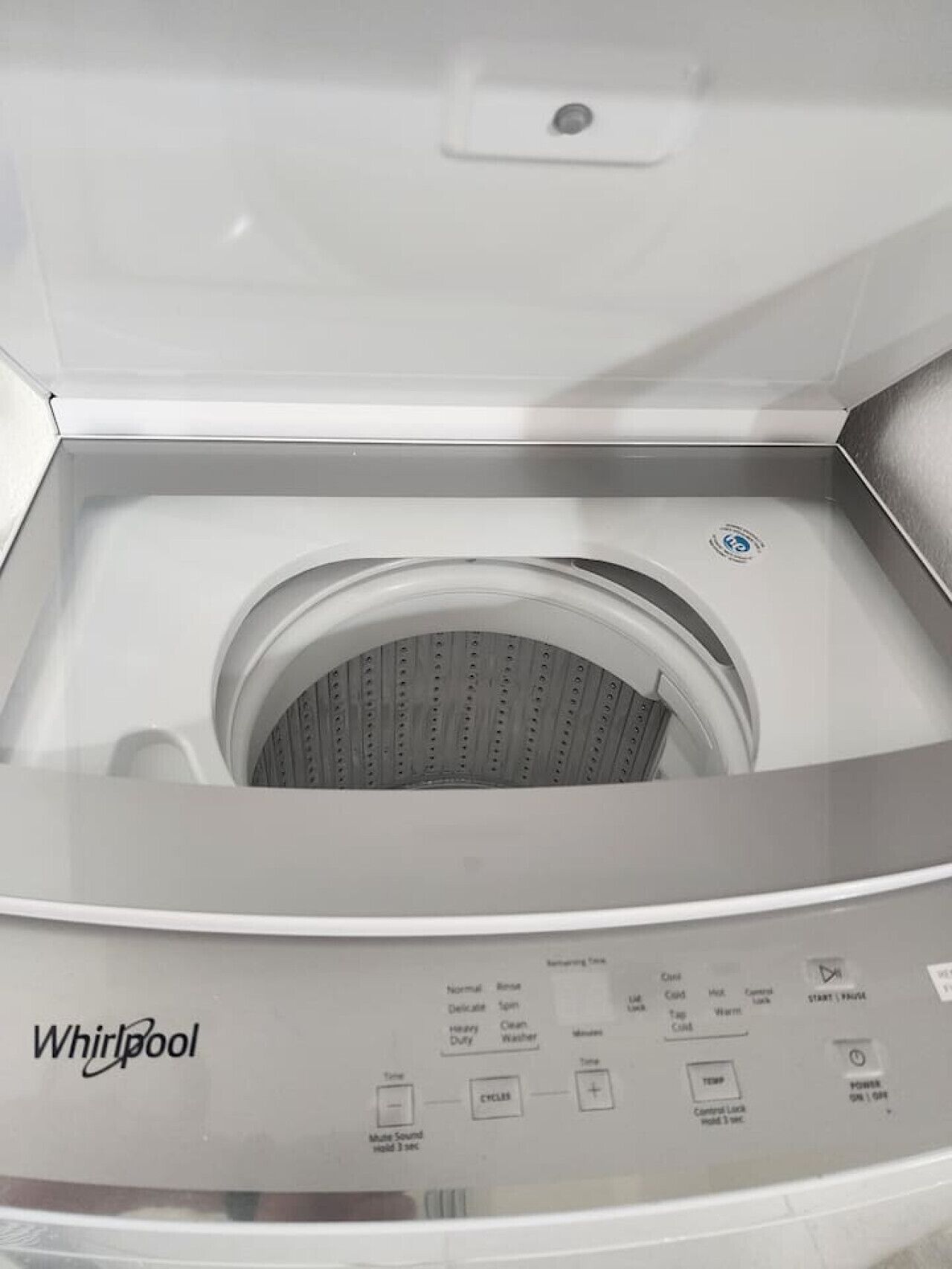 A Whirlpool washing machine with a control panel featuring buttons for various functions like start, pause, and power.