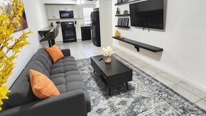 Ein modernes Wohnzimmer mit einer Couch, einem Couchtisch und einem an der Wand befestigten Flachbildfernseher.