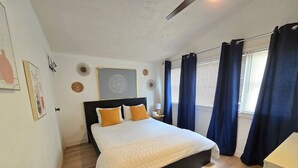 Ein Schlafzimmer mit einem Bett, einem Nachttisch, einer Wanduhr und einem Fenster mit Vorhängen.