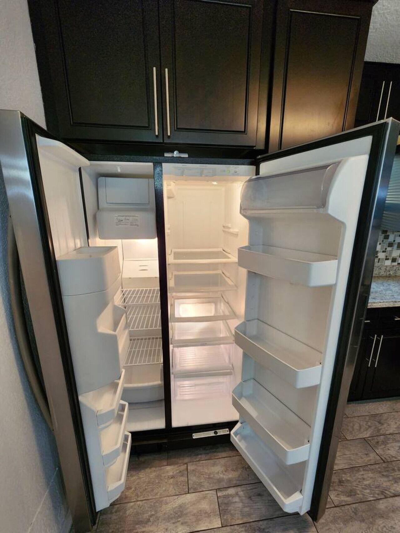 A modern kitchen with a built-in refrigerator, white cabinetry, and a tiled backsplash.