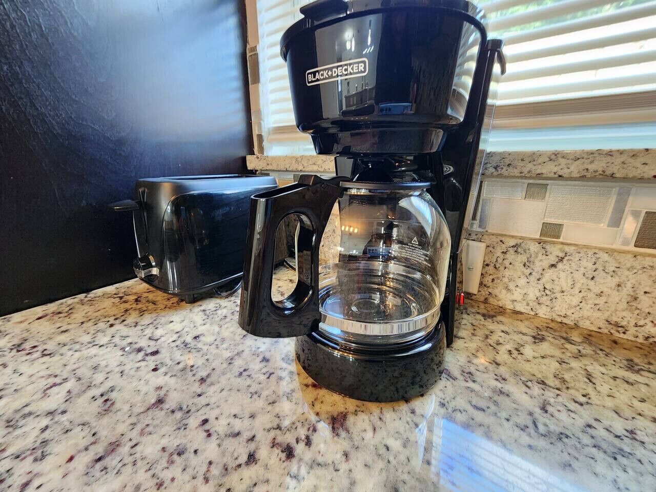 A coffee maker on a granite countertop.