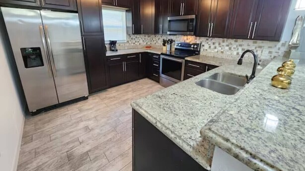 A modern kitchen with dark wood cabinets, stainless steel appliances, and granite countertops. - CasaDelaney DT Sodo district. Renovated Sleeps 16 (Orlando)