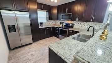 A modern kitchen with dark wood cabinets, stainless steel appliances, and granite countertops.