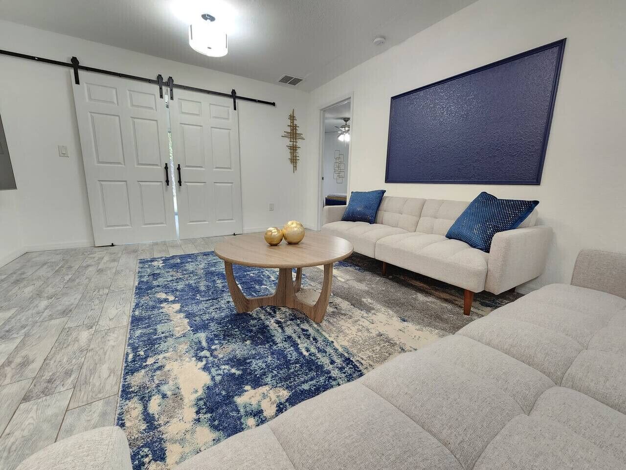 A living room with a sofa, a coffee table, and a blue patterned rug.