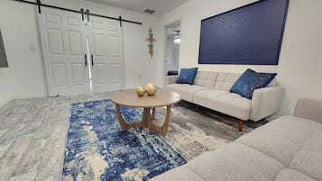 A living room with a sofa, a coffee table, and a blue patterned rug.