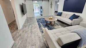 A modern living room with a sofa set, a coffee table, and a TV mounted on the wall. - CasaDelaney DT Sodo district. Renovated Sleeps 16 (Orlando)