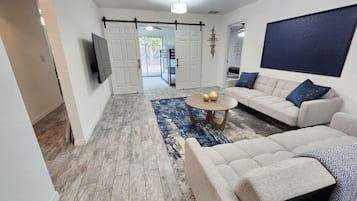 A modern living room with a sofa set, a coffee table, and a TV mounted on the wall.