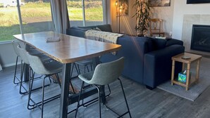 Una sala de estar moderna con una mesa de comedor, sillas, un sofá, un televisor y una chimenea.