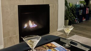 Una sala de estar con chimenea, dos copas de martini, una revista y un posavasos de corcho.