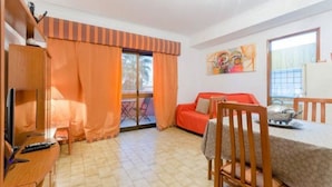 A cozy living room with a sofa, a dining table, and a TV. - Next to Lisbon 100m from Beaches & Surf (Costa da Caparica)