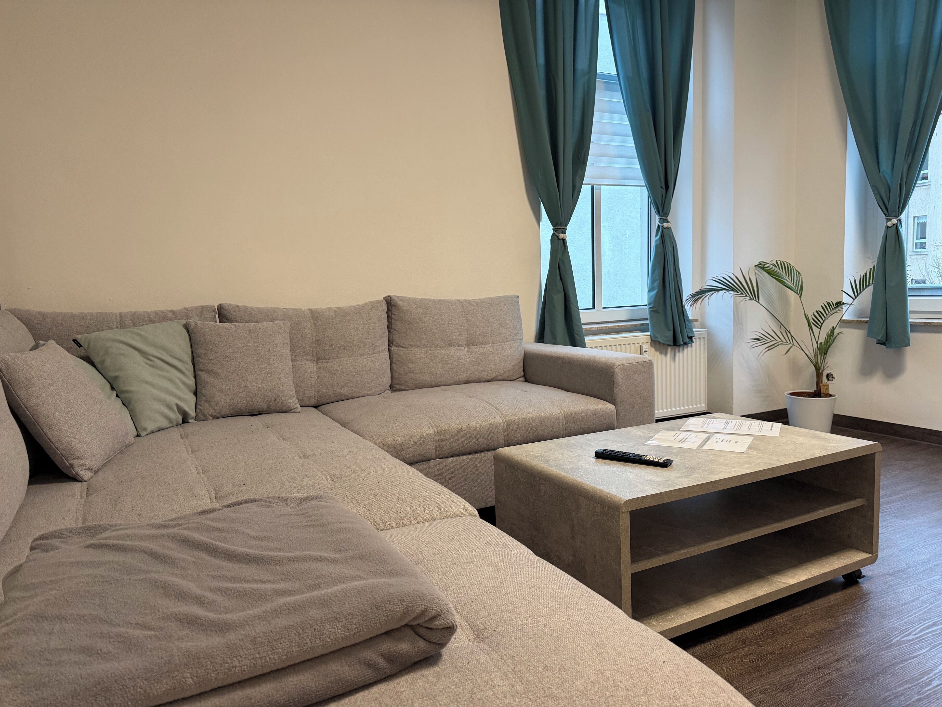 Ein modernes Wohnzimmer mit einer Eckcouch, einem Couchtisch und einer Topfpflanze.