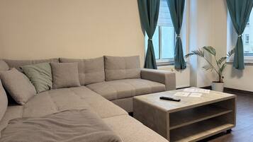 Ein modernes Wohnzimmer mit einer Eckcouch, einem Couchtisch und einer Topfpflanze.
