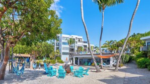 Un resort con posti a sedere all'aperto, palme e un edificio con balconi.
