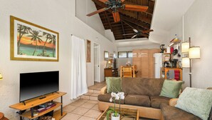 A living room with a flat-screen TV, a sofa, a coffee table, and a ceiling fan. - Tropical Getaway North Shore Princeville Studio (Princeville)