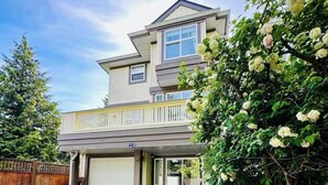 A two-story house with a garage, a covered porch, and a driveway leading to the entrance. - Private Studio: Separate Entry, Washroom & Living Room (Surrey)