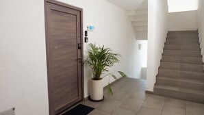 Een modern interieur met een houten deur, een kamerplant, een trap en een bordje aan de muur met het kamernummer 301.