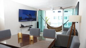 Een moderne hotelkamer met een zithoek, een bank, een hangmat en een televisie aan de muur.