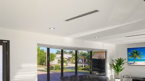 A modern living room with a large window, a sectional sofa, a round ottoman, and a flat-screen TV. - Tropical Heaven Punta Gorda (Punta Gorda)