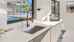 A modern kitchen with a large window, a built-in sink, and a countertop with a coffee station. - Tropical Heaven Punta Gorda (Punta Gorda)