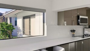 A modern kitchen with a large window, a built-in microwave, and two bar stools. - Tropical Heaven Punta Gorda (Punta Gorda)