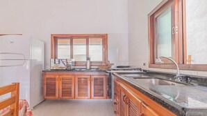 A compact kitchen with wooden cabinets, a built-in oven, and a sink. - Casa em Ubatuba com churrasqueira e varanda ampla (Ubatuba)