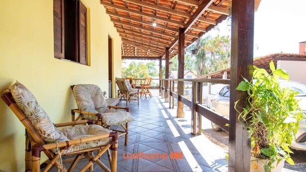 A covered outdoor seating area with bamboo chairs and a table, a potted plant, and a view of the street. - Sitio em Aracariguama com Piscina e Churrasqueira (Araçariguama)
