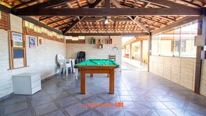 An indoor recreational area with a pool table, chairs, and a billiards rack. - Sitio em Aracariguama com Piscina e Churrasqueira (Araçariguama)