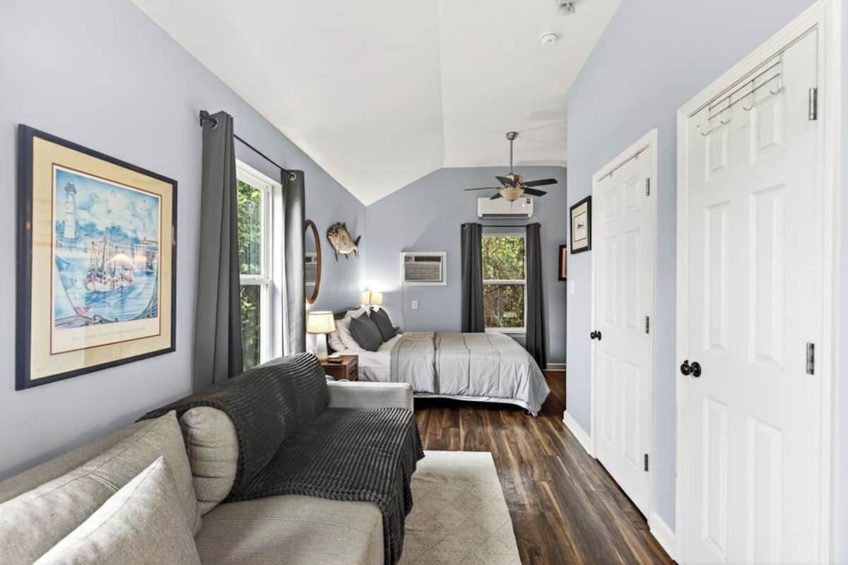 A bedroom with a bed, a nightstand, a lamp, a ceiling fan, and a window with curtains.