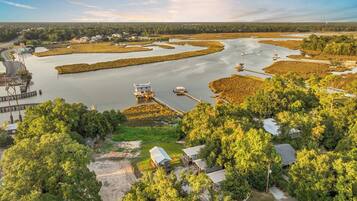 An aerial view of a coastal area with a marina, boats, and residential buildings surrounded by dense vegetation.