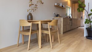 A modern kitchen with wooden cabinets, a dining area with a wooden table and chairs, and a potted plant. - Highland Cows/Wood-Fired Hot Tub/Stunning Views (Logan)