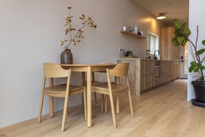 A modern kitchen with wooden cabinets, a dining area with a wooden table and chairs, and a potted plant. - Highland Cows/Wood-Fired Hot Tub/Stunning Views (Logan)