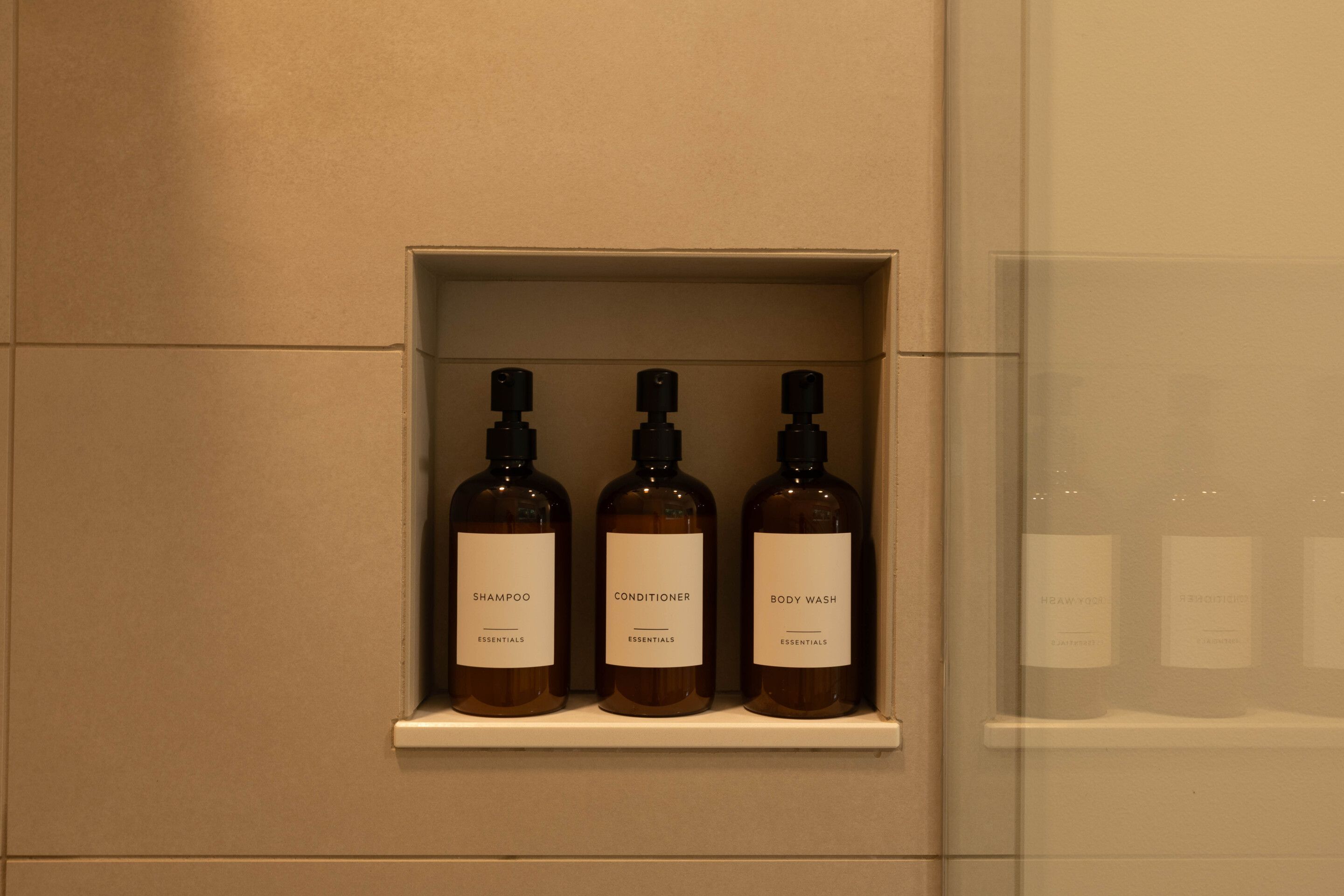 A shelf with three bottles of shampoo, conditioner, and body wash.