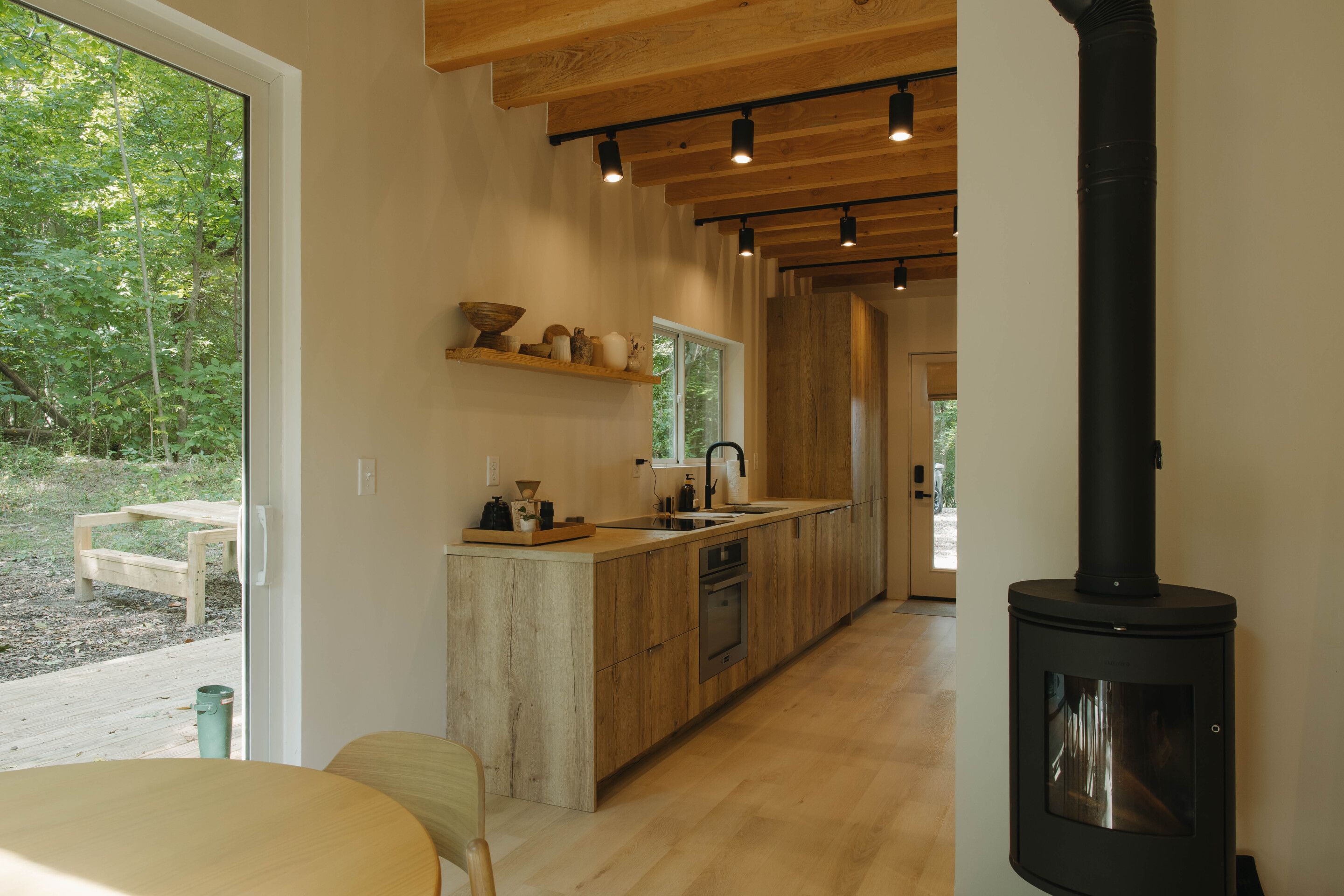 A modern kitchen with wooden cabinetry, a central island, and a wood-burning stove.