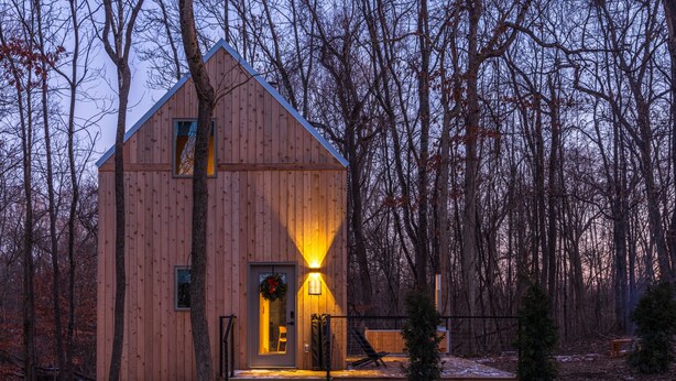 Une cabane en bois avec un toit en pente, une porte d’entrée et un petit porche.