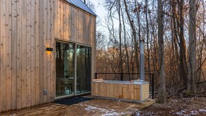 Une cabane en bois avec une porte en verre, une terrasse et un espace sauna.