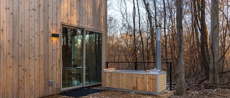 Une cabane en bois avec une porte en verre, une terrasse et un espace sauna.
