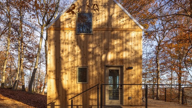 Une cabane en bois avec un petit porche, une porte et une fenêtre.