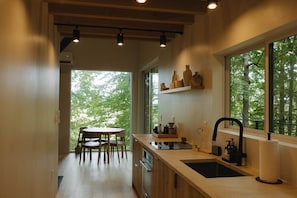 A modern kitchen with a wooden countertop, a sink, and a window overlooking a forest. - Where the Woods Meets the Pasture/Private/Hot Tub (Logan)